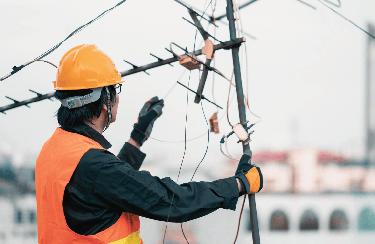 Technician in safety gear repairing television antenna
